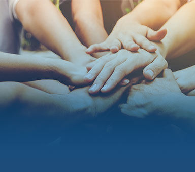 Hände, die übereinander gestapelt sind, symbolisieren Gemeinschaft und Zusammenarbeit.