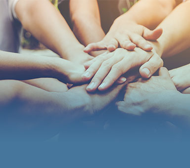 Mehrere Hände, die übereinander liegen, symbolisieren Zusammenarbeit und Gemeinschaft.